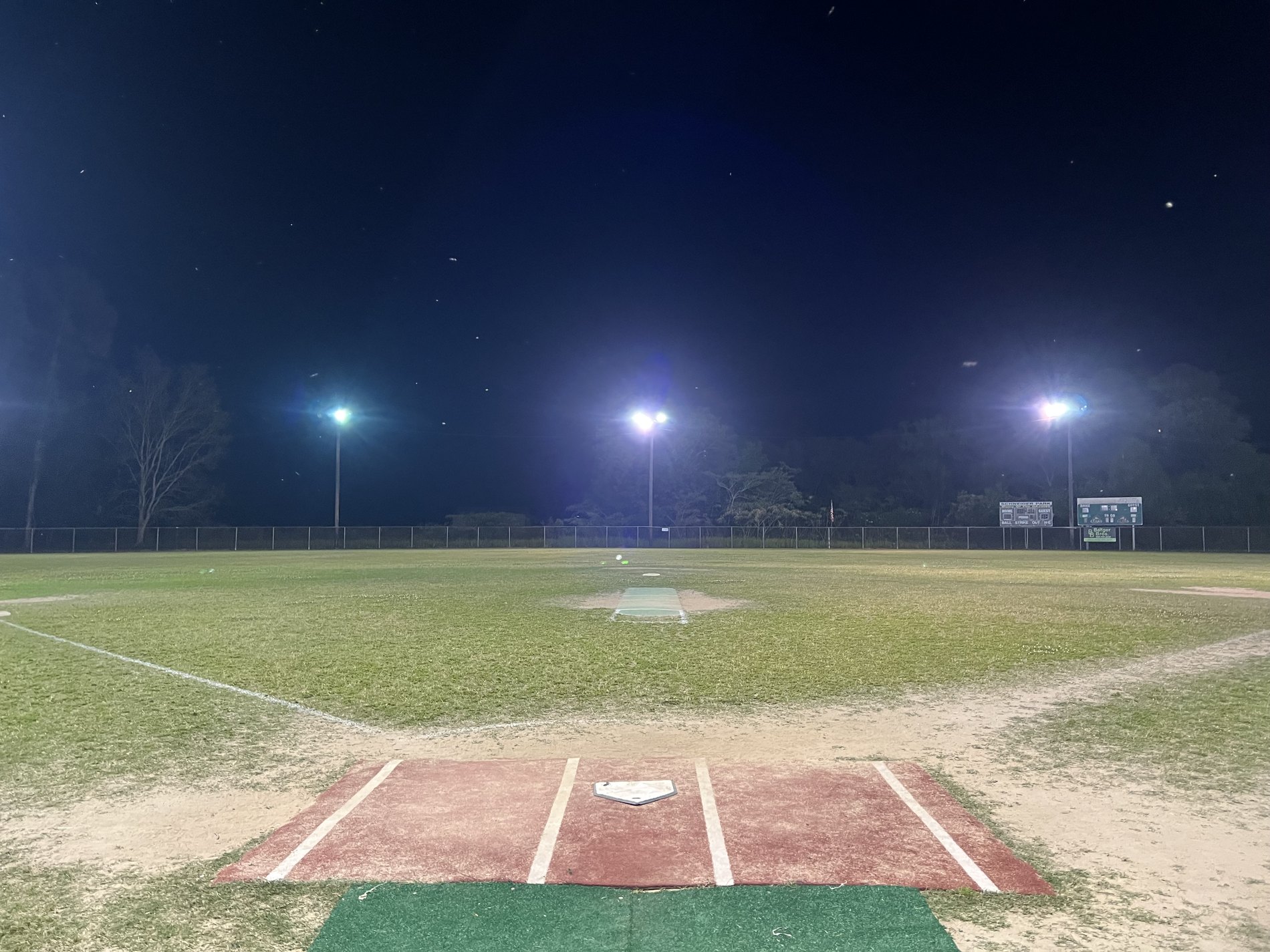 Nolan Adams, Sr. Field at night, seen from behind home plate with the field lights on