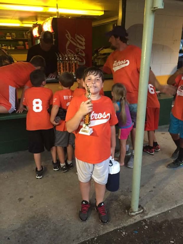 Children in orange Astros shirts gathered at the concession stand counter, one holding a trophy