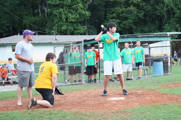 A batter at home plate during a game while players and coaches look on
