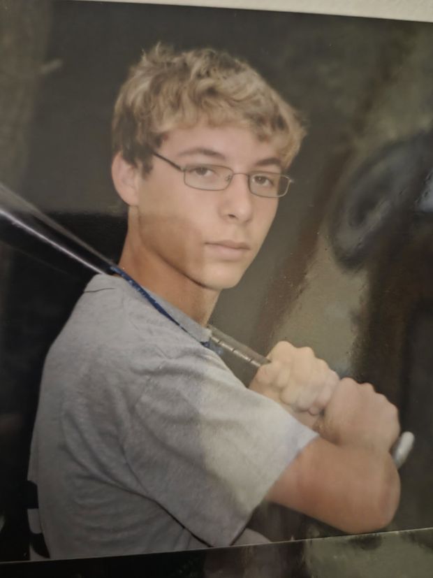A photographed print of a teenager in glasses holding a bat over his shoulder