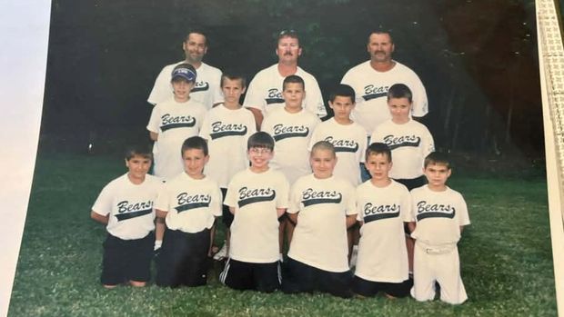 A printed team photograph of players in cream Bears shirts in three rows, with three adult coaches standing at the back