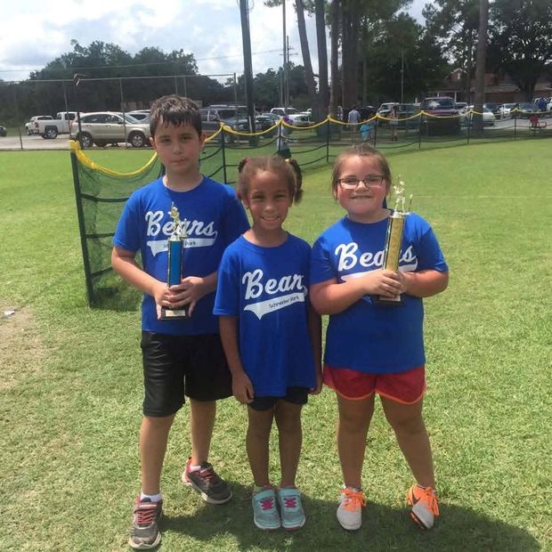 Three small children in blue Bears shirts, two holding trophies