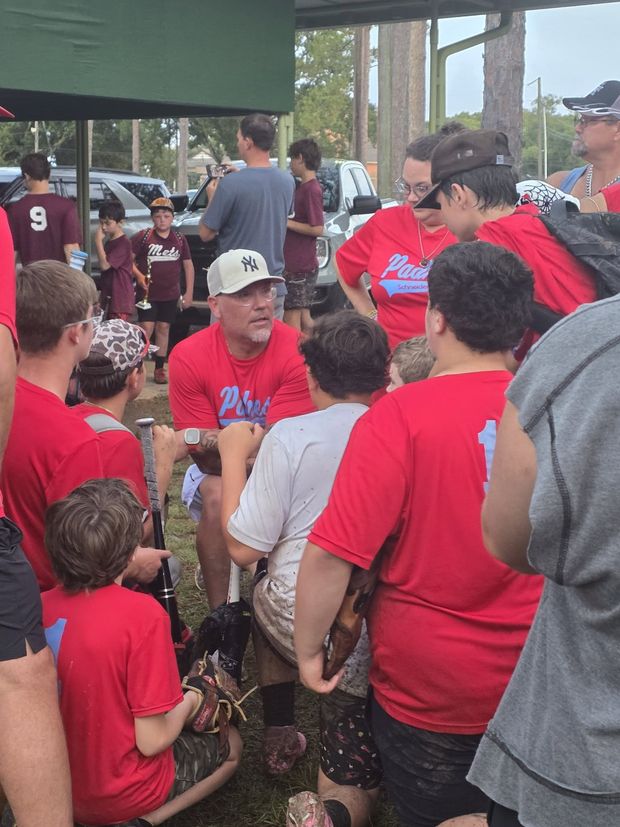 Players and families in red shirts gathered under the pavilion