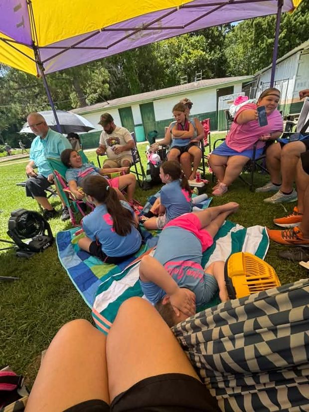 Families and players relaxing on blankets and chairs under a canopy