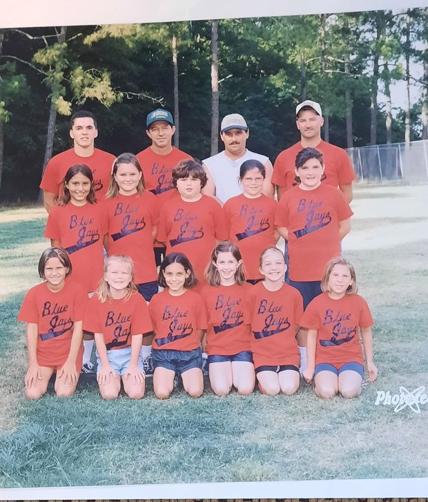 A printed team photograph of children in red Blue Jays shirts posed in rows on the grass