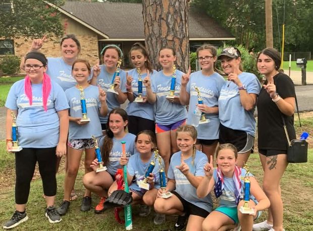 A team in light blue shirts with their coaches holding blue trophies