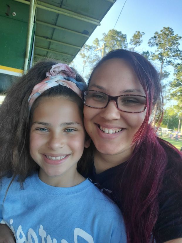A woman and a girl with a braid smiling close together in a selfie