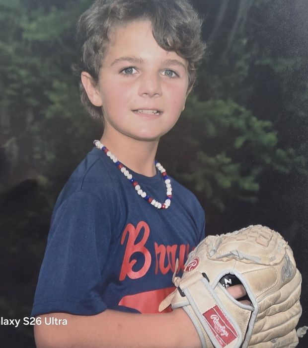 A printed portrait of a boy in a navy Braves shirt holding a worn glove