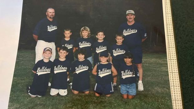 A printed team photograph of young players in navy Bulldogs shirts in two rows, with two adult coaches standing behind them