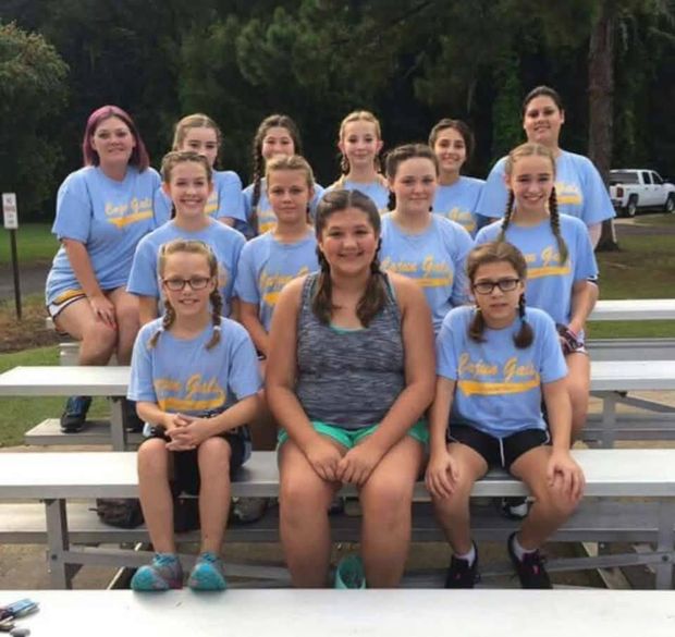 A girls team in light blue Cajun Girls shirts sitting together on the bleachers