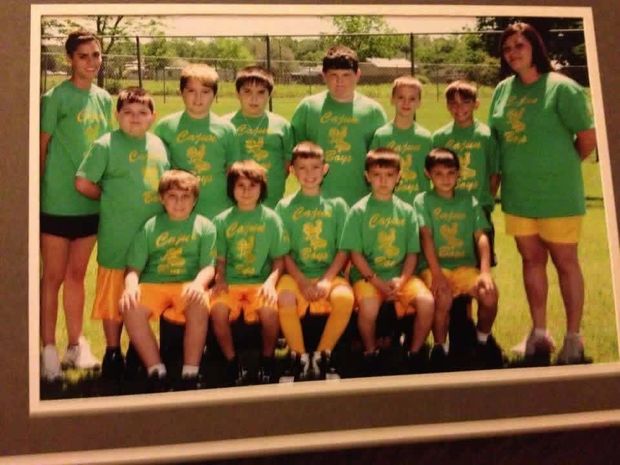 A printed team photograph of players in green Cajuns shirts posed in rows