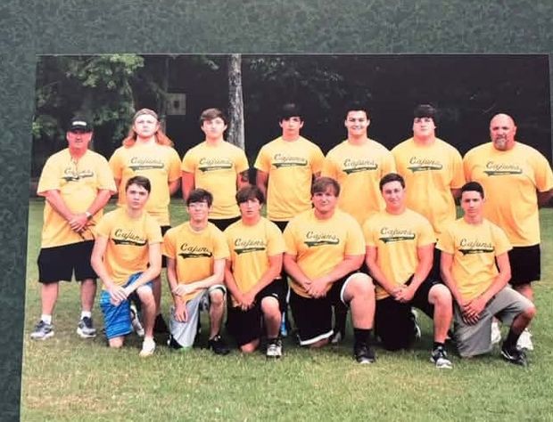 A printed team photograph of players in yellow Cajuns shirts in two rows with adult coaches standing at each end