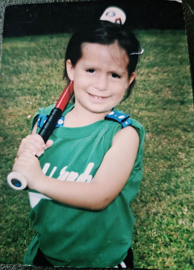 An old print of a small child in a green shirt with a bat over one shoulder and a cap slipping off