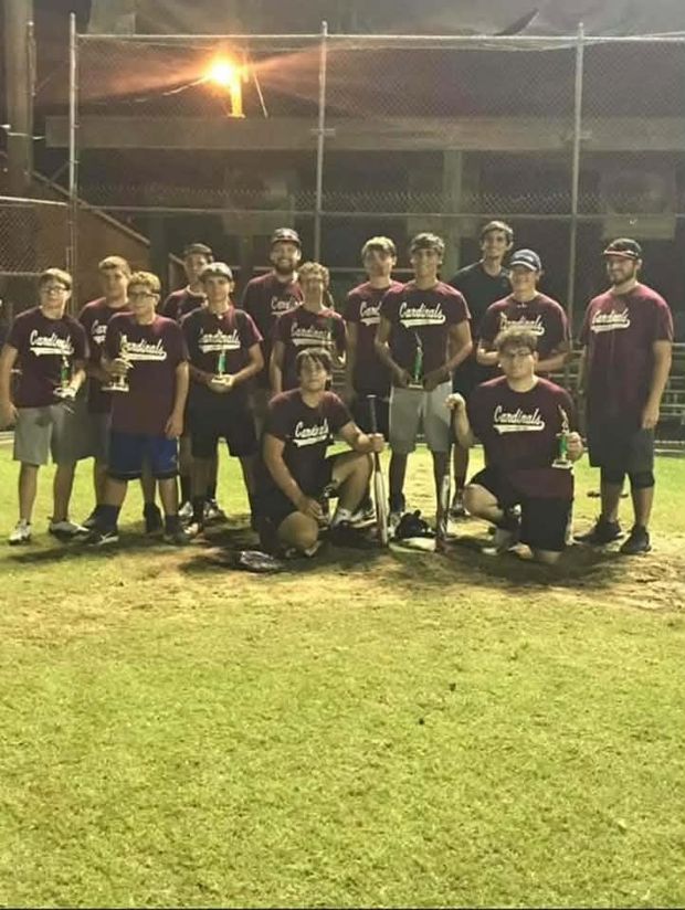 A team in maroon Cardinals shirts standing on the field at night holding trophies
