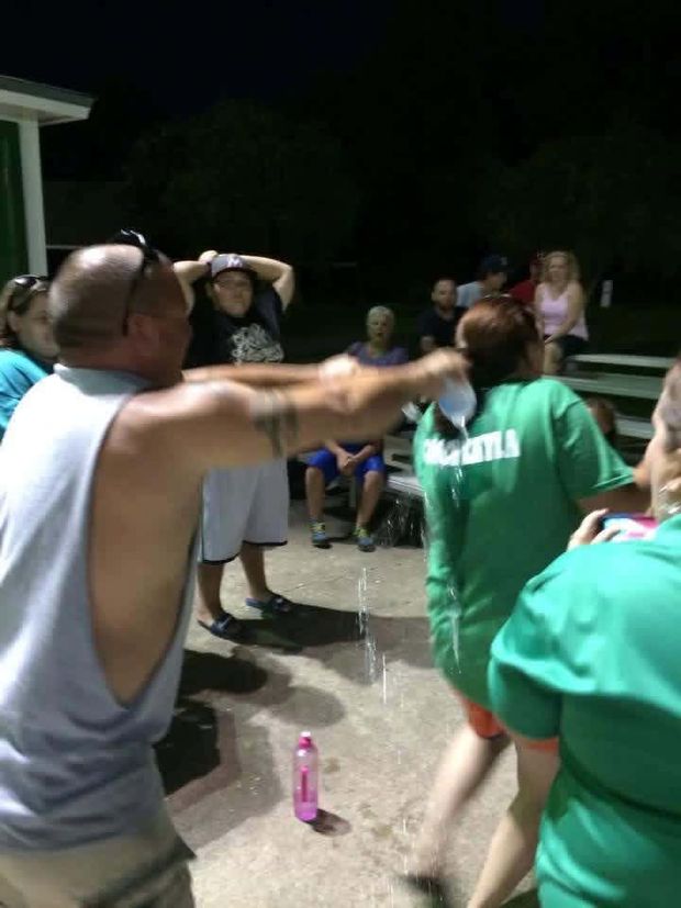 A crowd celebrating at night as water is poured over a player
