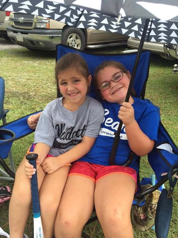 Two young girls in Wildcats and Bears shirts sharing a folding chair