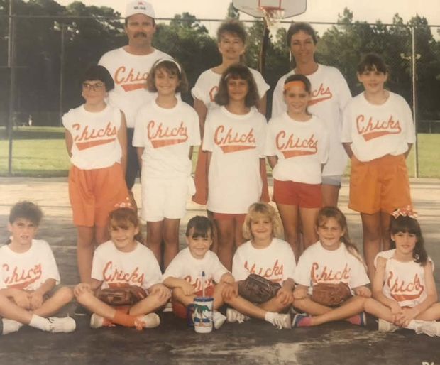 An old film print of a team in white Chicks shirts and orange shorts posed on the basketball court