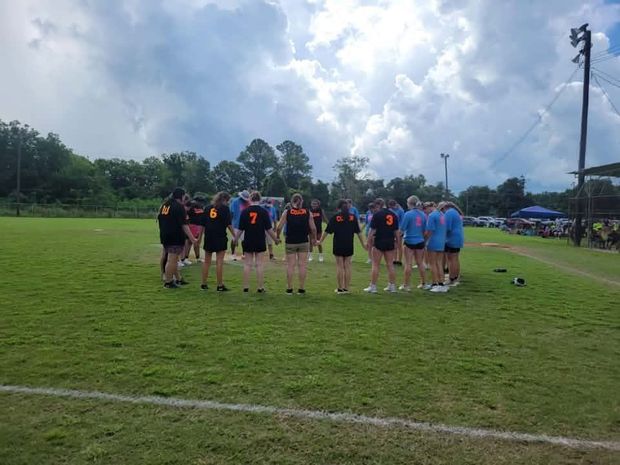 Players from both teams standing in a circle holding hands on the field