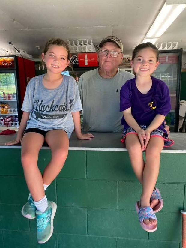 Two girls sitting on the concession stand counter beside an older man