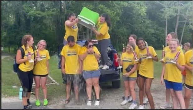 Players in yellow shirts dumping a cooler of water over someone by a truck