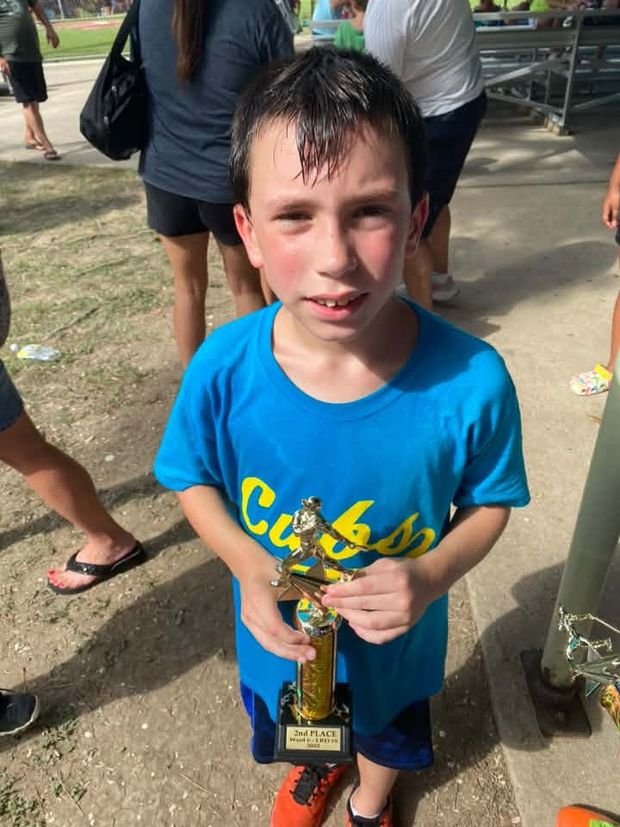 A boy in a blue Cubs shirt holding a second place trophy