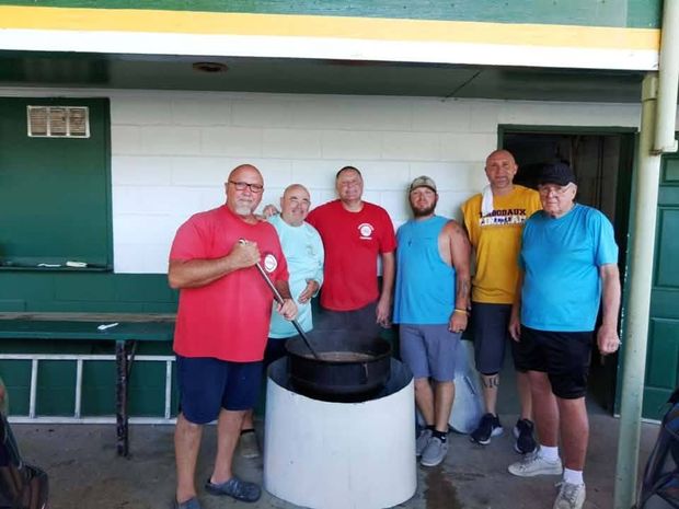 Men gathered around a cooking pot at the concession stand during the dedication