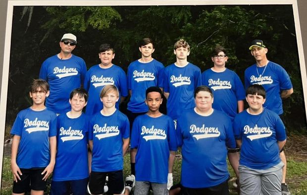 A printed team photograph of a team in blue Dodgers shirts, two rows with two coaches behind