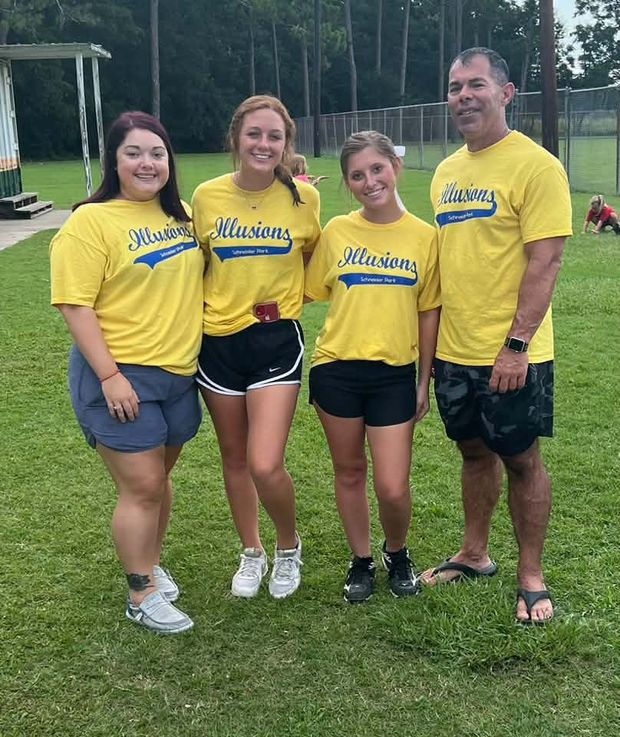 Four people in matching yellow Illusions team shirts standing together on the grass