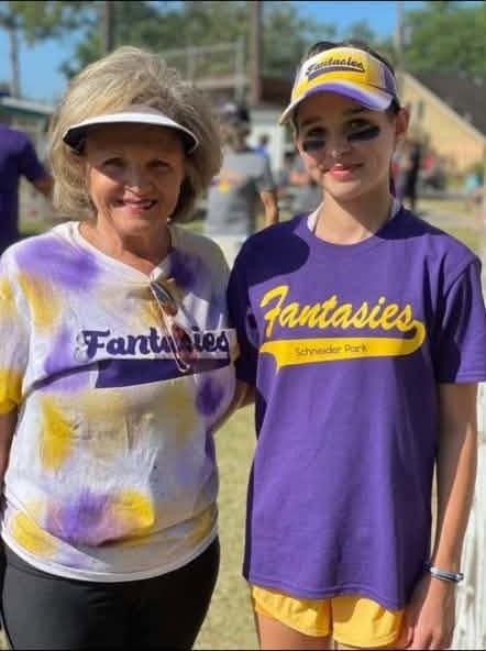 An older woman in a tie-dyed Fantasies shirt standing with a young player in purple