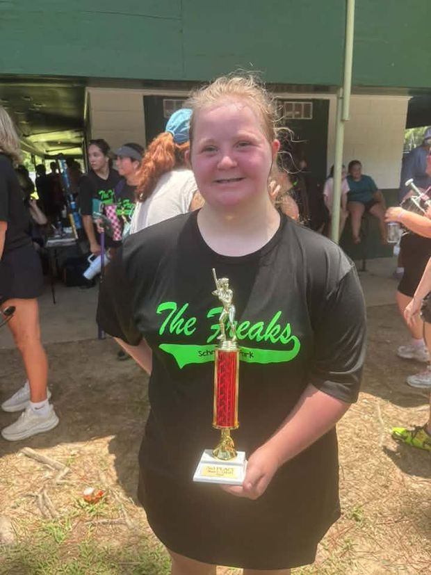 A girl in a black Freaks shirt holding a trophy