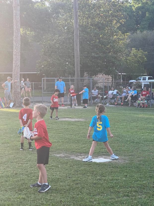 A batter in blue at the plate and a fielder in red, with spectators along the fence behind