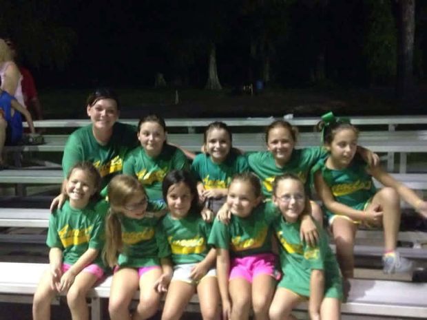 A girls team in green shirts sitting together on bleachers at night