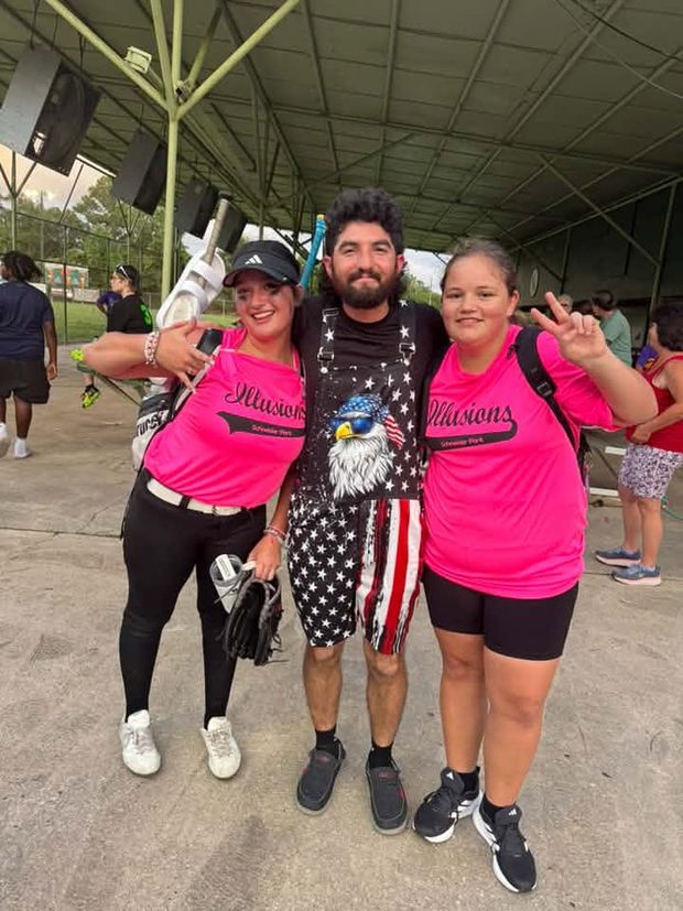 Two players in Illusions shirts standing with a man under the pavilion