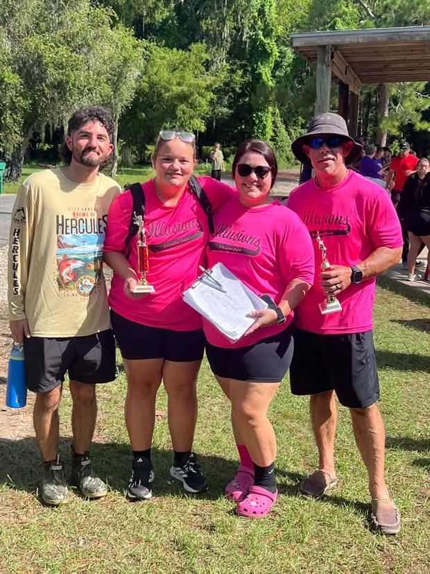 Two players in pink Illusions shirts holding trophies beside their coaches