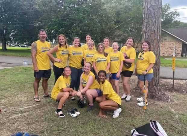 A team in yellow Illusions shirts posed casually on the grass with their equipment