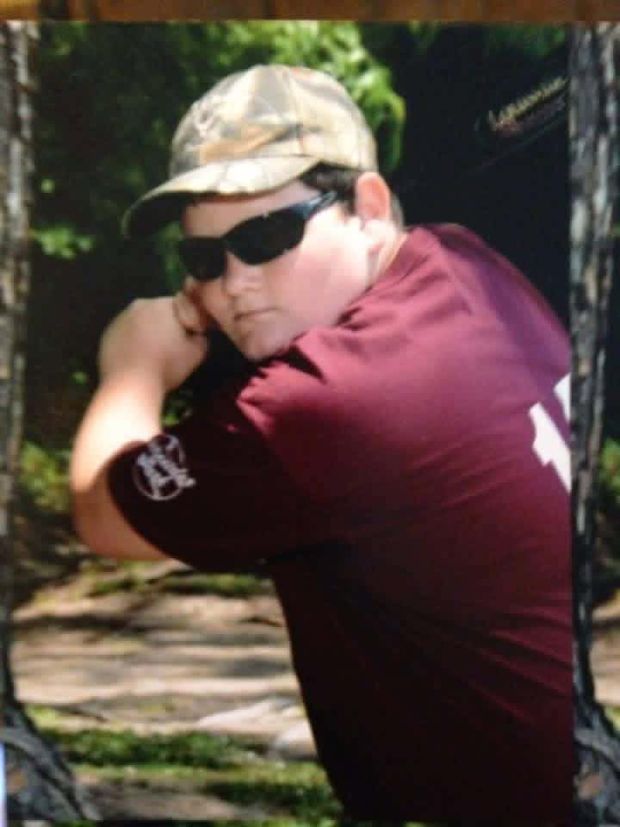 A photographed print of a boy in a maroon shirt in a batting pose outdoors