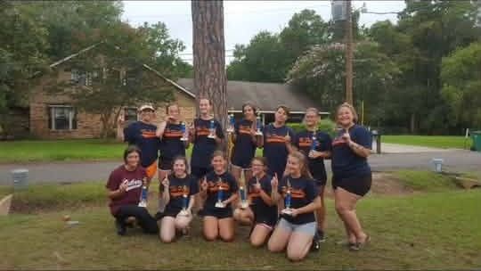 A team in navy shirts posed together on the grass