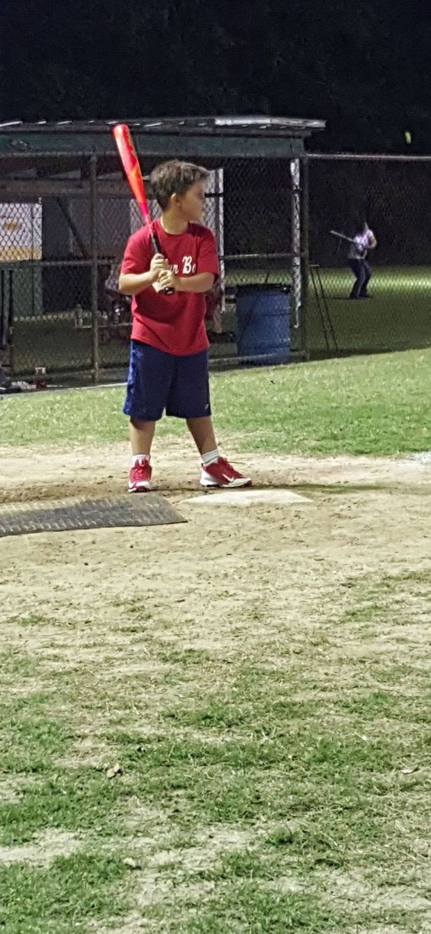 A boy in a batting stance at the plate at night