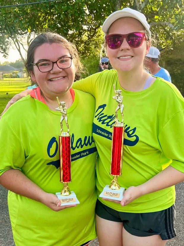 Two players in neon green Outlaws shirts each holding a red trophy