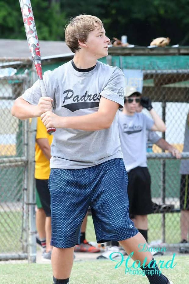 A teenager in a grey Padres shirt in a batting stance at the plate
