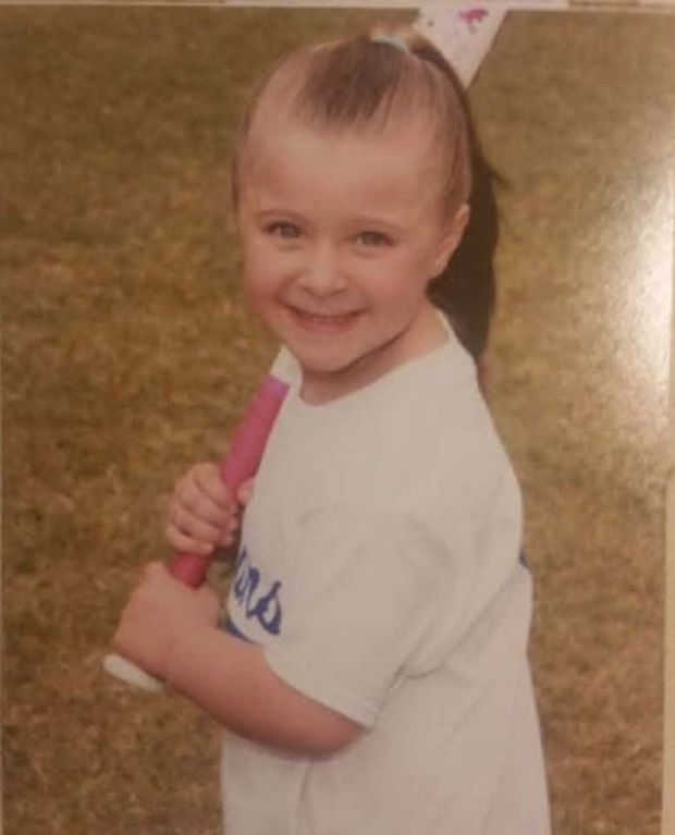 A warm faded print of a little girl in a white shirt holding a pink bat