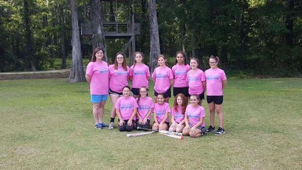 A girls team in pink shirts posed in two rows on the grass