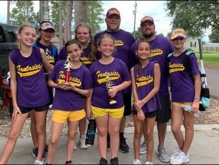A team in purple shirts posed with parents and coaches