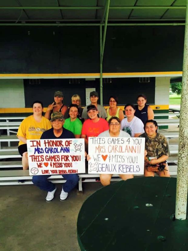 A group on the bleachers holding two hand-made signs in honor of Mrs Carol Ann