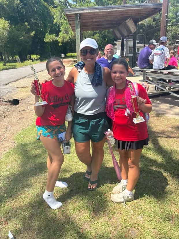 A woman with two children in red shirts, one holding a trophy
