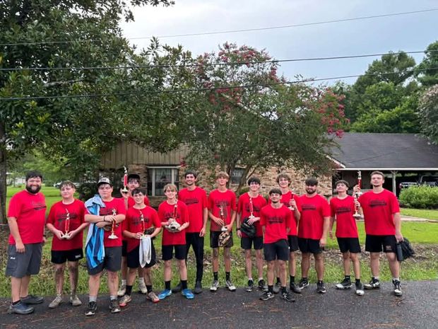 Teenage players in red shirts standing on the road holding trophies