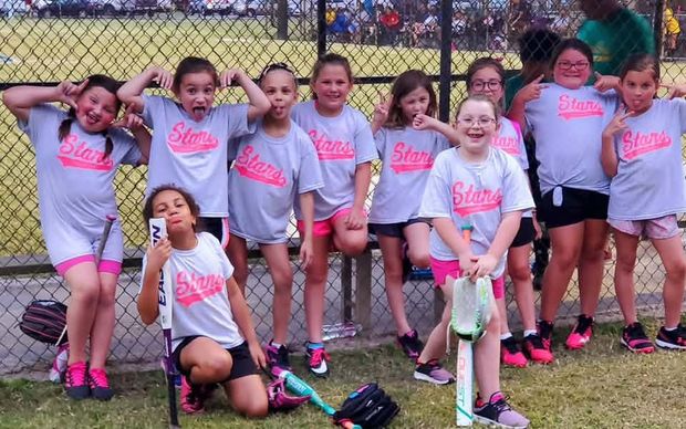 Girls in grey and pink Stars shirts making faces on the bench by the fence
