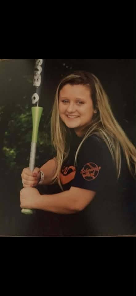 A printed portrait of a girl holding a bat against a dark studio background