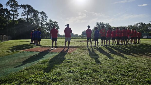 Teams lined up along the base paths at sunset