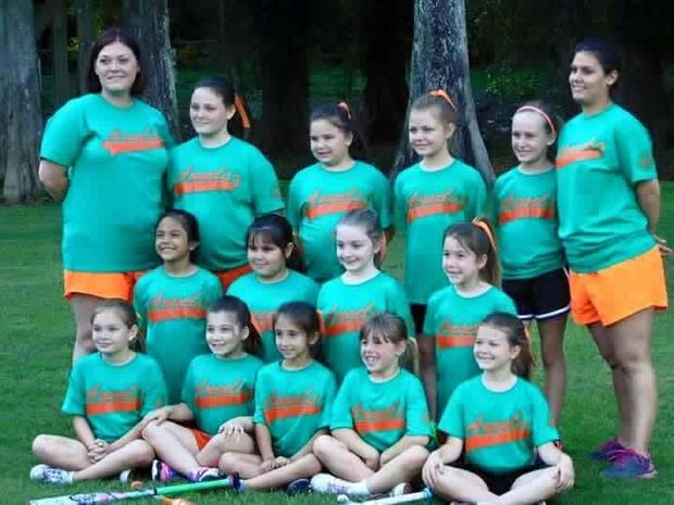 A girls team in teal and orange shirts posed together